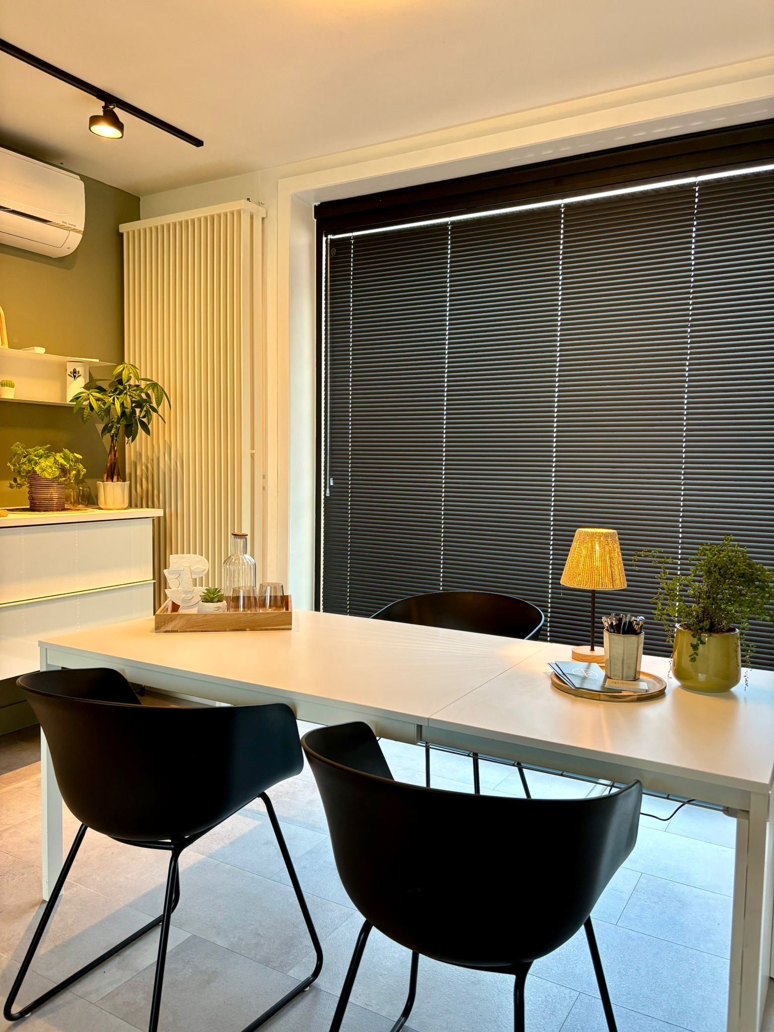 Consultatieruimte met tafel, planten en warme verlichting