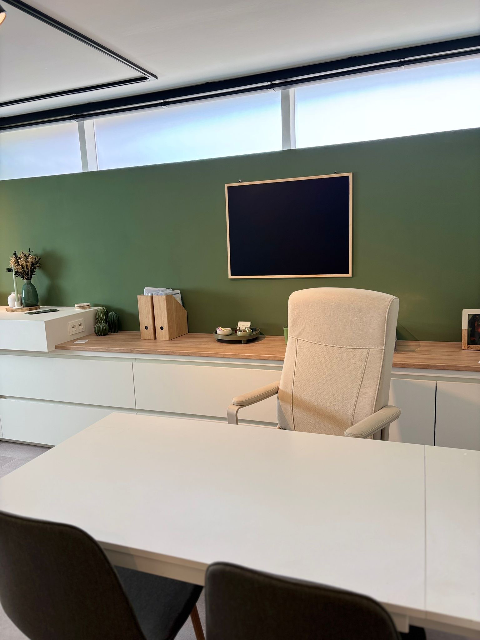 Consultatieruimte met groene wand en vergadertafel